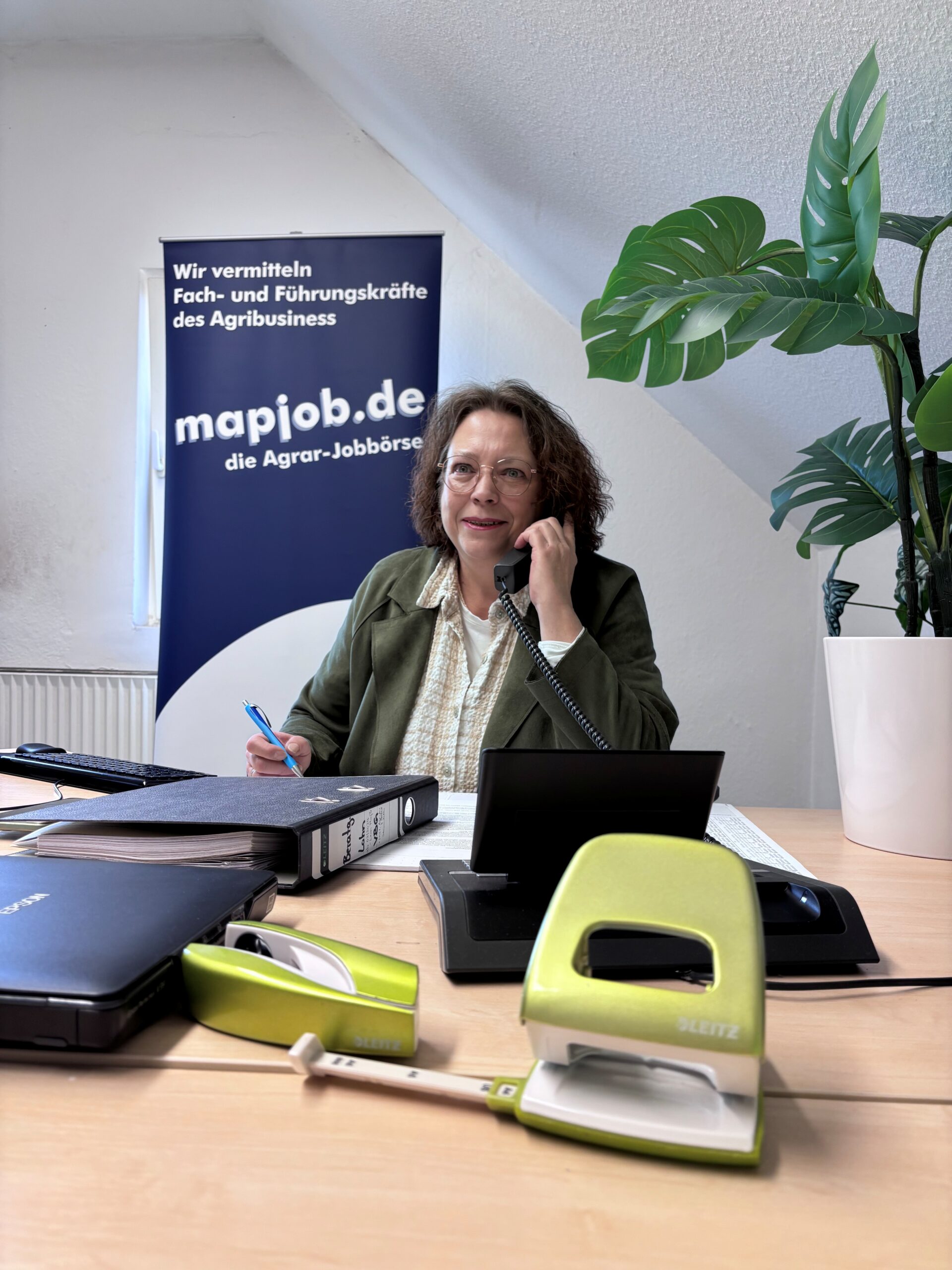 Frau Schwunk telefoniert lächelnd an ihrem Schreibtisch. Wir stehen für direkten Kontakt und Unterstützung bei der Suche nach neuen Stellenangeboten.