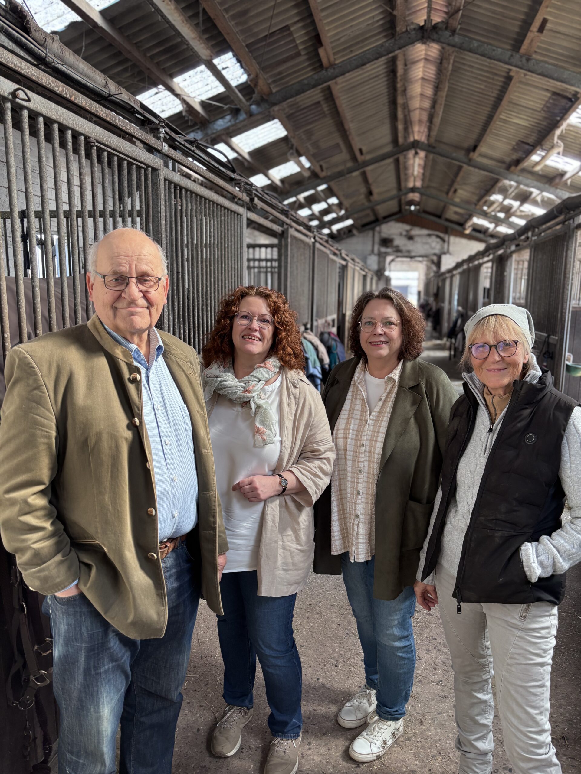 Das Mapjob.de Team in einer hellen Stallgasse. Symbolbild für Teamarbeit und Jobs in der modernen Pferdewirtschaft.